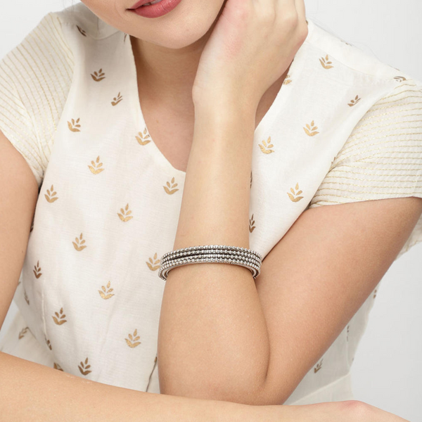 A woman showcasing a silver-plated bangle on her wrist.